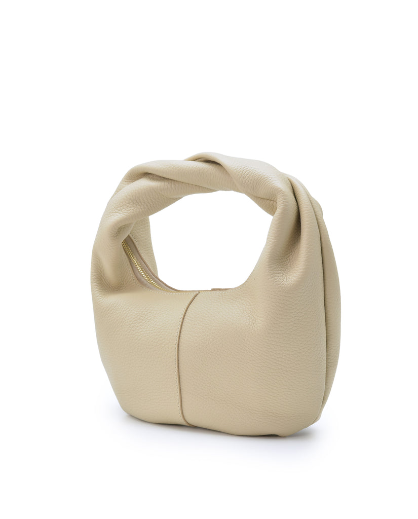 Imagen oblicua de bolso hobo mini de mano de piel color beige Leandra. Bolsos de piel fabricados en Ubrique Made in Spain