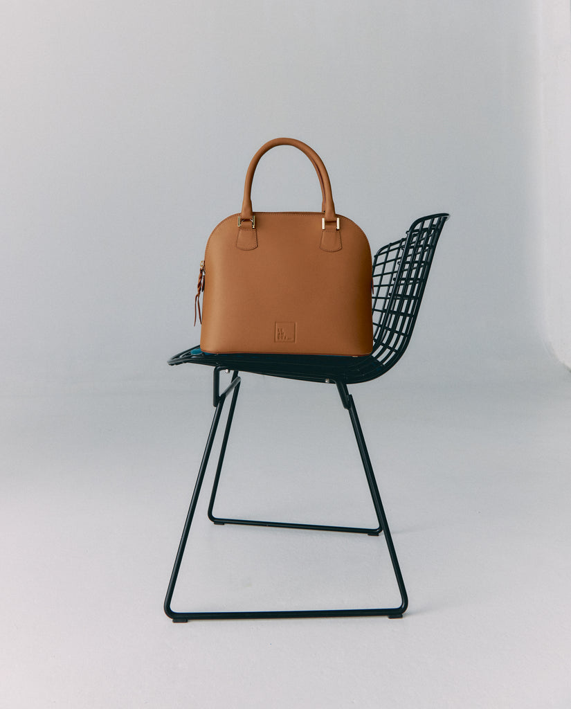 Imagen bodegón de bolso de mano  de piel en color camel Leandra. Bolsos de piel a la venta en leandrabrand.com fabricados en Ubrique, España