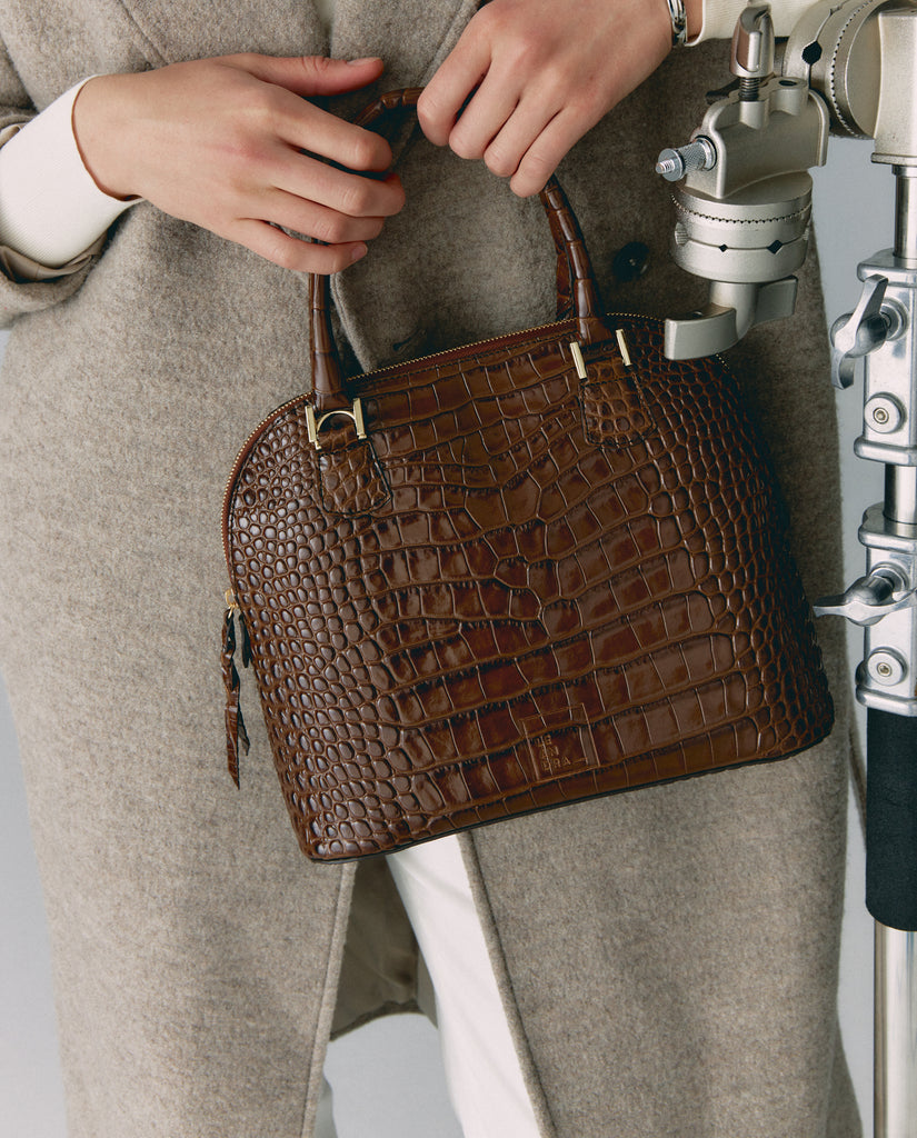 Imagen de modelo 9 con bolso de piel grabada en coco marrón de mano Leandra. Bolsos fabricados en Ubrique, España a la venta en leandrabrand.com