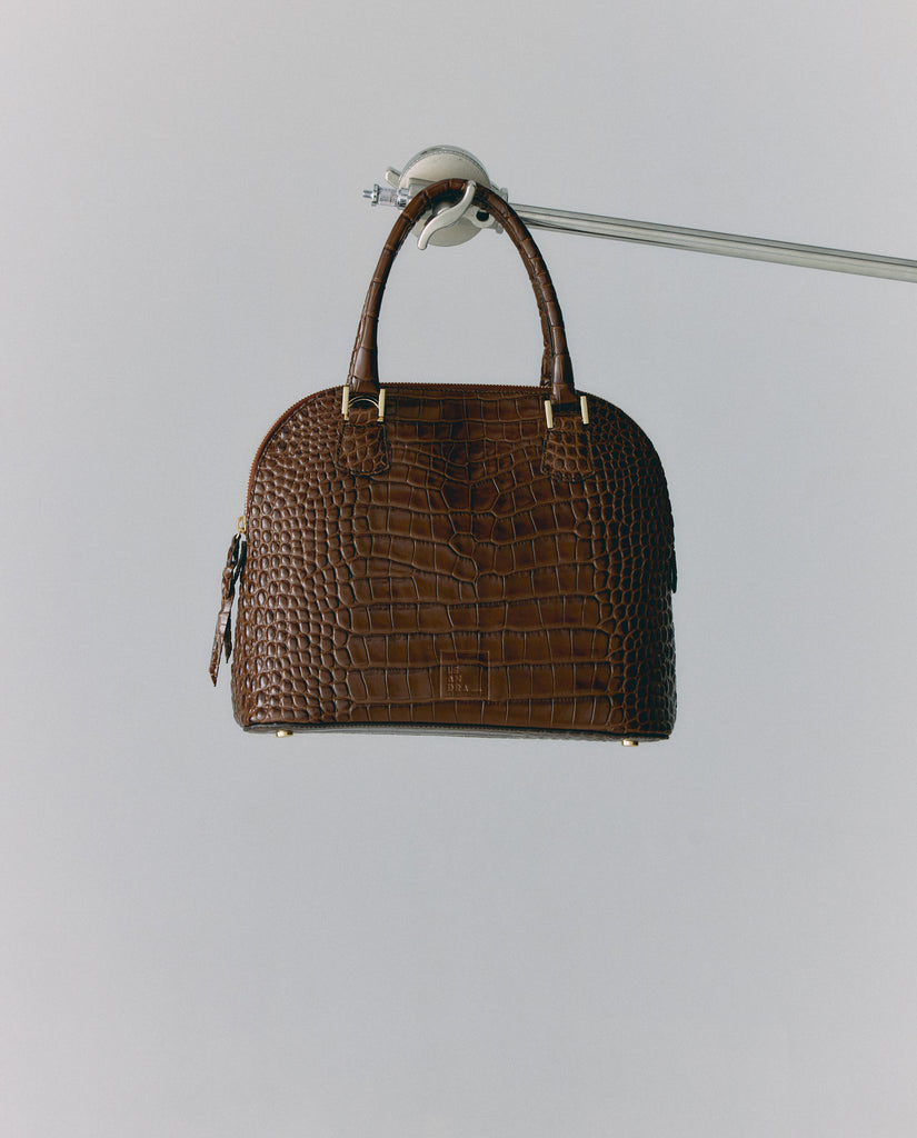 Imagen bodegón de bolso de mano de piel grabada en coco color marrón Leandra. Fabricado en Ubrique, España