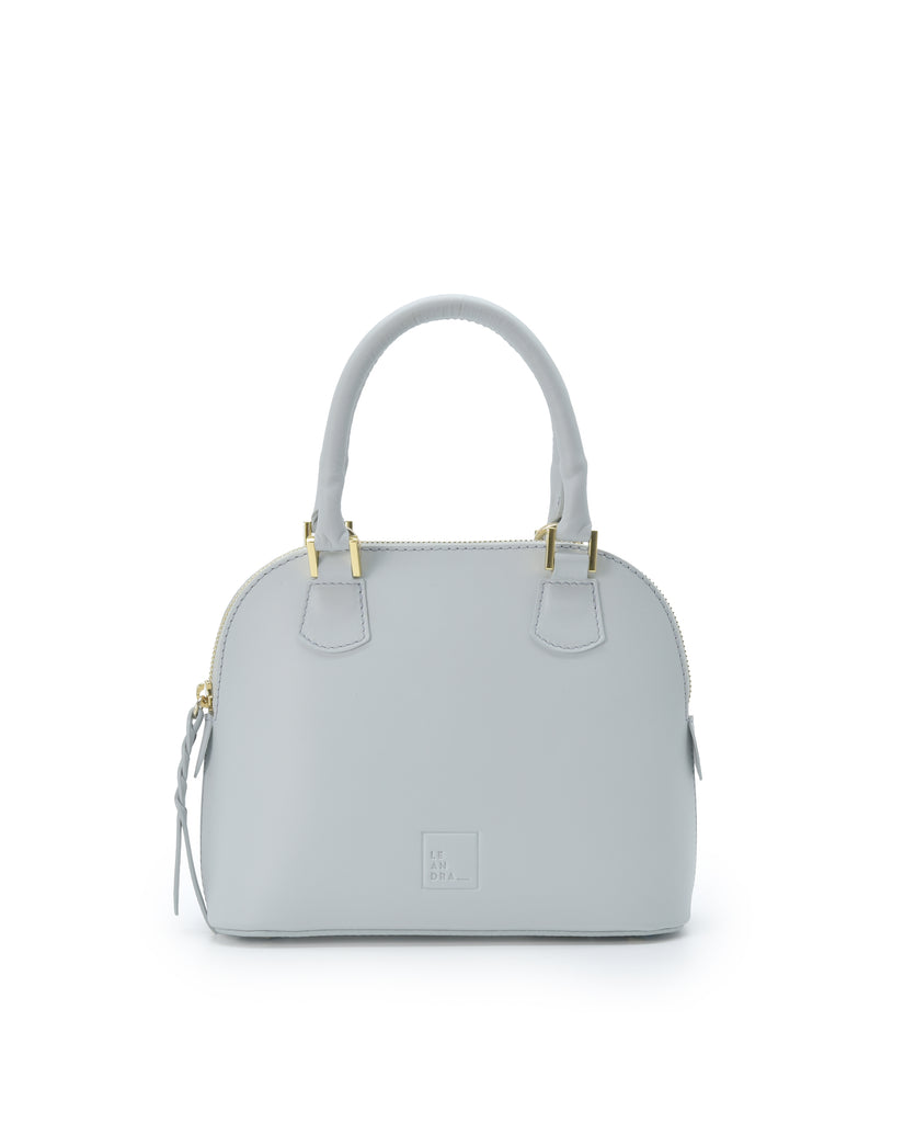 Imagen frontal con asa de mano del bolso de mano mini de piel color azul cielo Leandra. Bolsos de piel fabricados en Ubrique Made in Spain