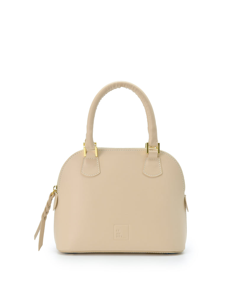 Imagen frontal con asa de mano del bolso de mano mini de piel color beige Leandra. Bolsos de piel fabricados en Ubrique Made in Spain