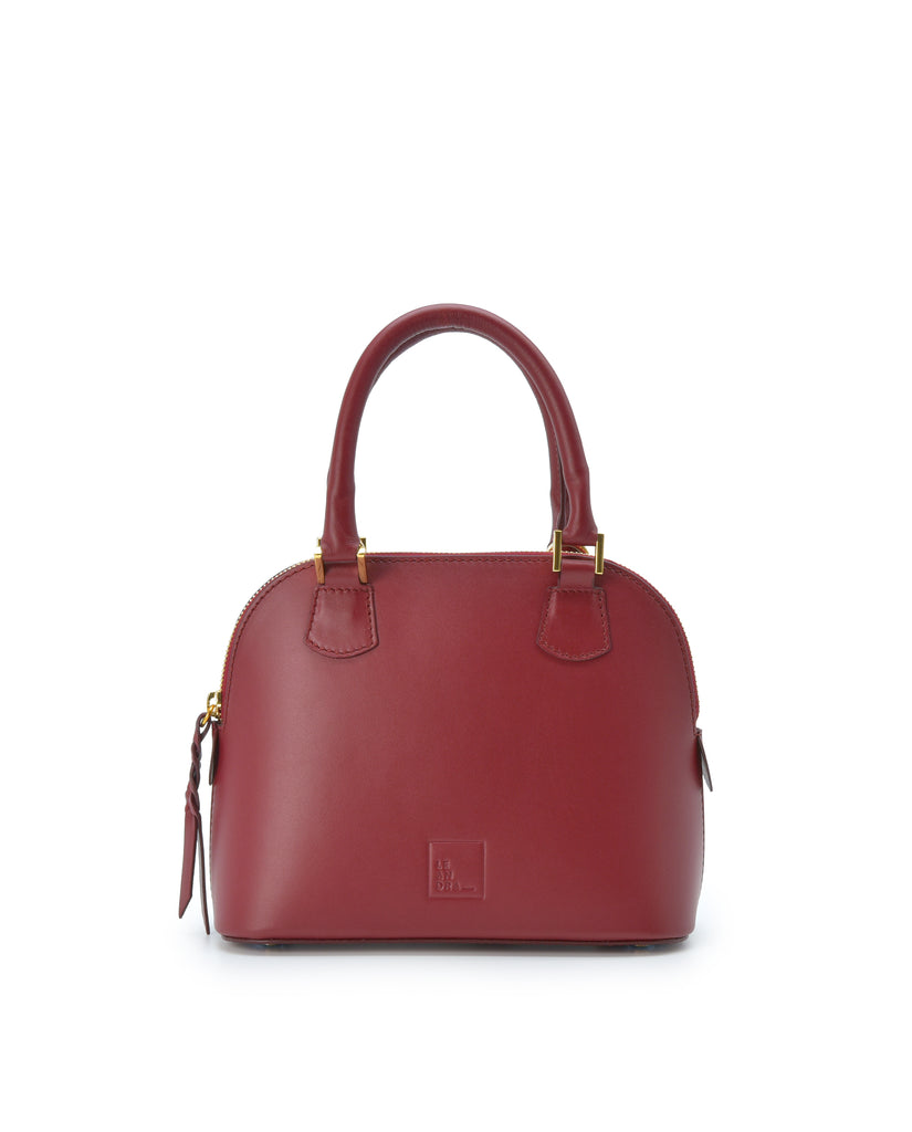 Imagen frontal con asa de mano del bolso de mano mini de piel color burdeos Leandra. Bolsos de piel fabricados en Ubrique Made in Spain