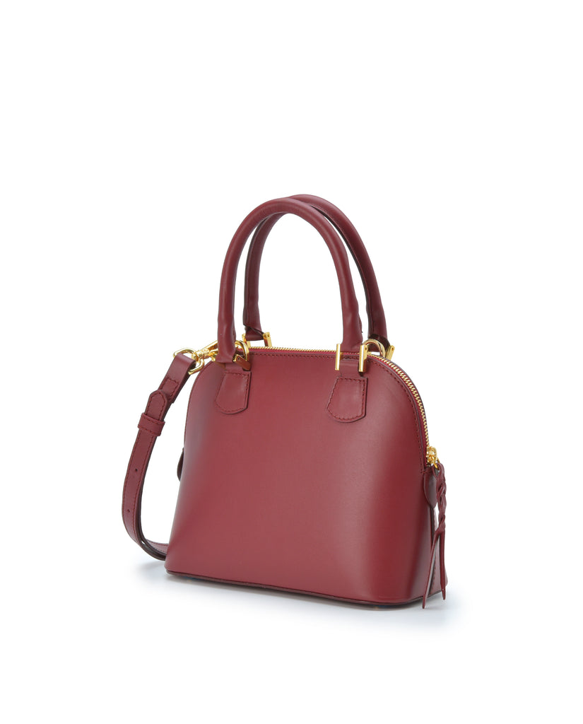 Imagen lateral de bolso de mano mini de piel color burdeos  Leandra. Bolso made in Spain