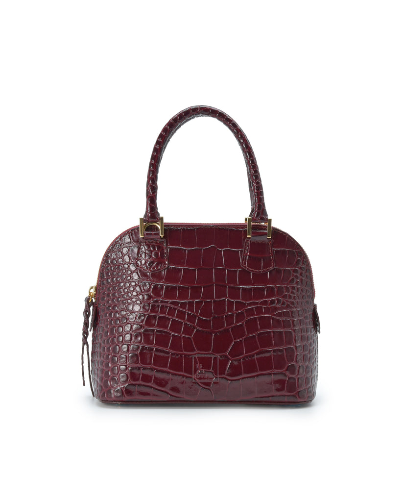 Imagen frontal con asa de mano del bolso de mano mini de piel grabada en coco color burdeos Leandra. Bolsos de piel fabricados en Ubrique Made in Spain