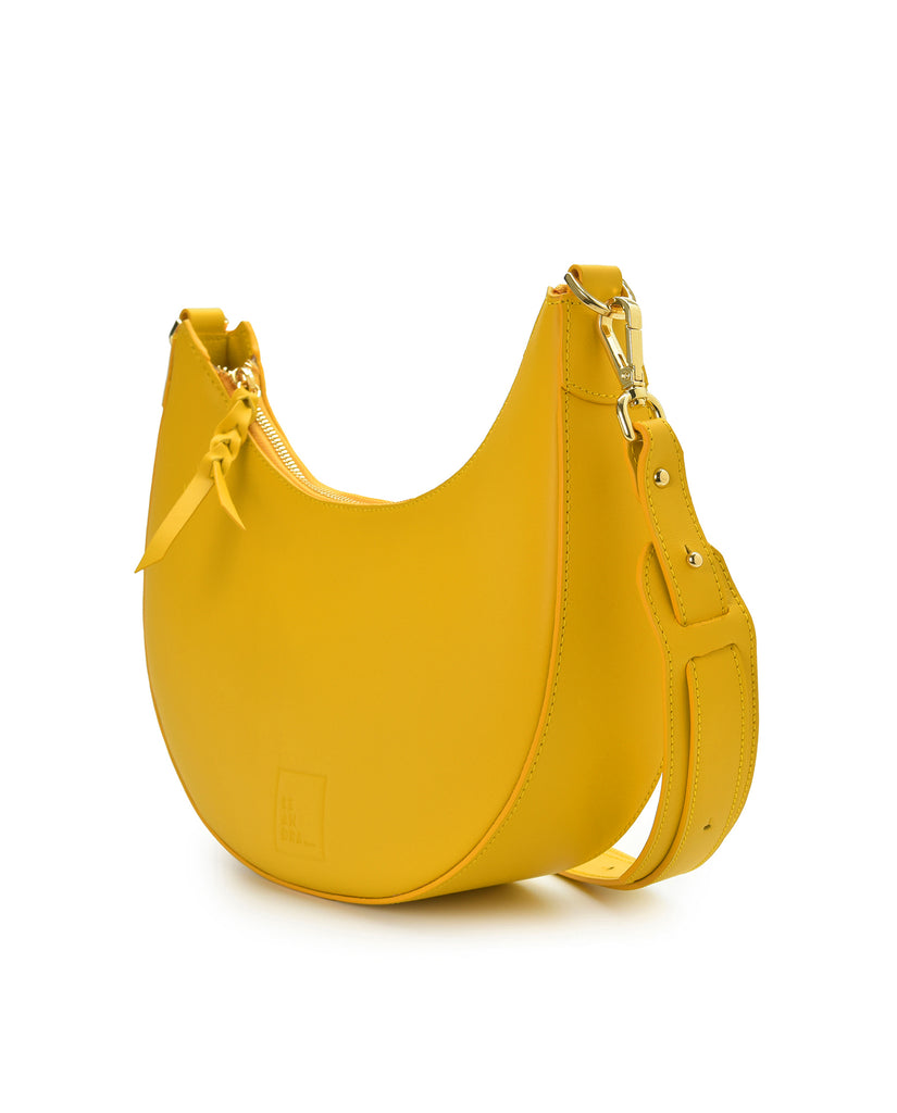 Bolso multiposición con forma de media luna de piel color amarillo Leandra. Fabricado en Ubrique España