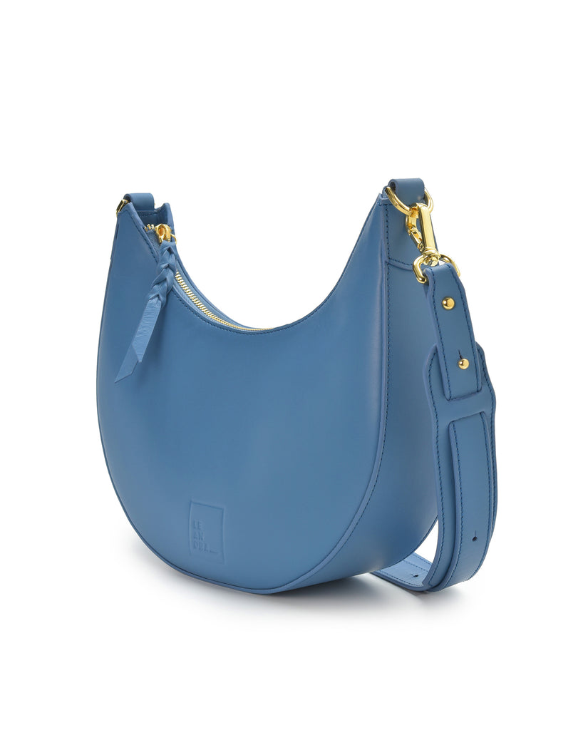 Imagen lateral de bolso media luna de piel color azul Leandra. Made in Spain 