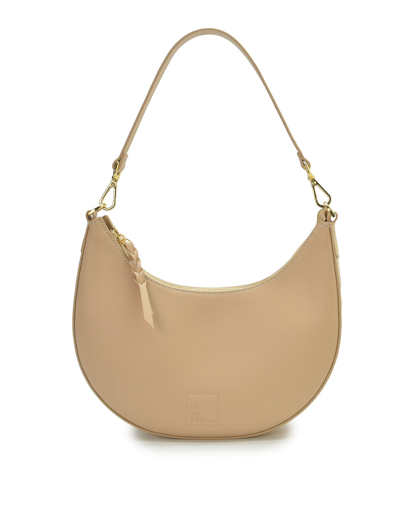 Imagen frontal de bolso media luna beige Leandra. Bolso de hombro multiposición con forma de media luna de piel color beige Leandra.