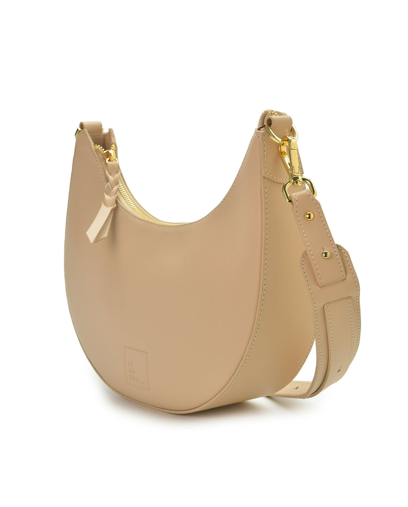 Imagen lateral de bolso media luna beige Leandra. Bolso multiposición con forma de media luna de piel color beige Leandra.