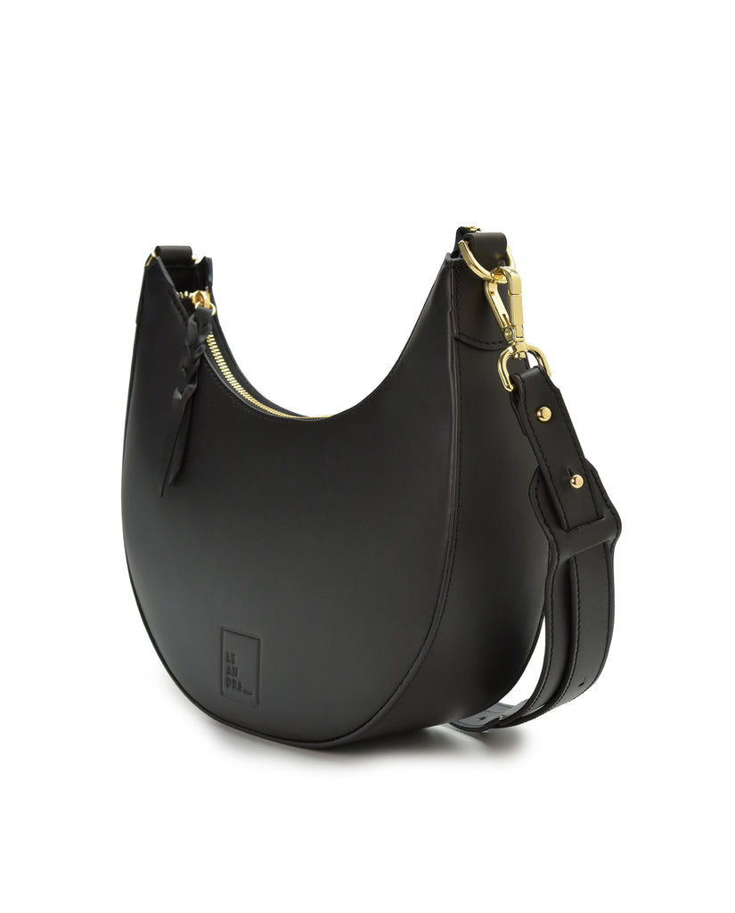 Imagen bolso en oblicuo. Bolso multiposición con forma de media luna de piel color negro Leandra. Made in Spain 
