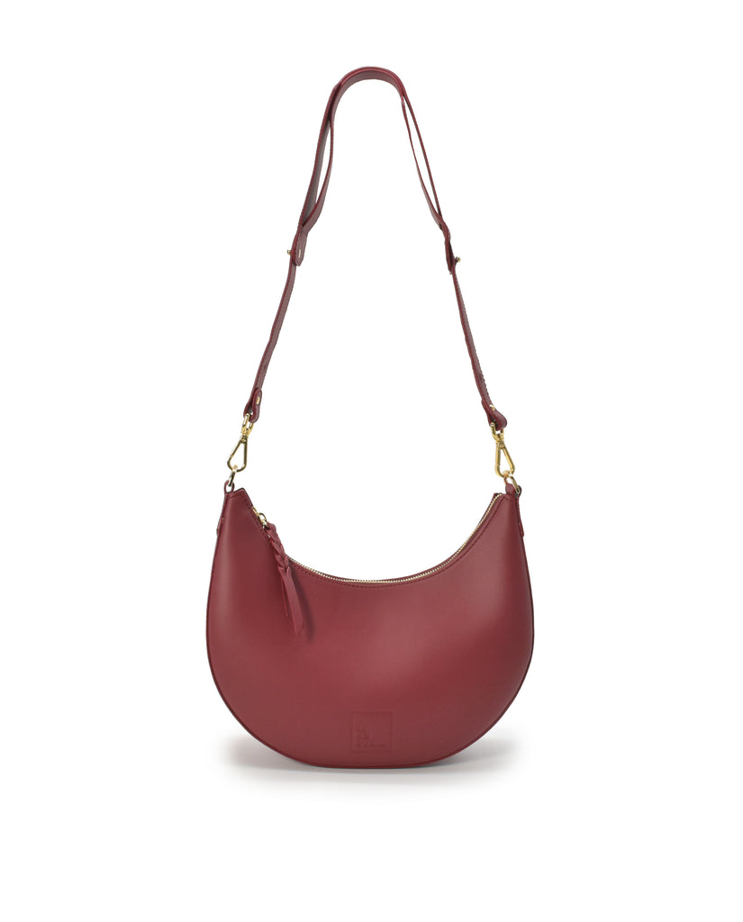 Imagen asa larga de bolso de hombro multiposición con forma de media luna de piel color burdeos Leandra.