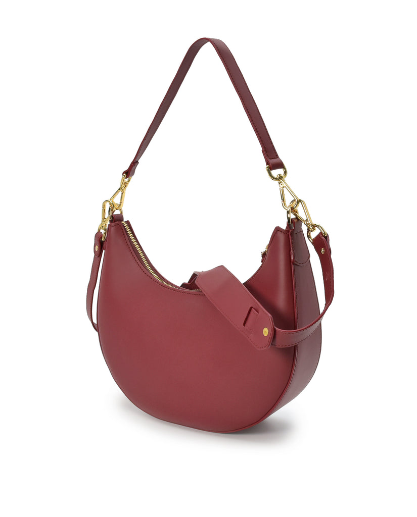 Imagen detalle ambas asas en oblicuo bolso media luna de bolso de hombro multiposición con forma de media luna de piel color burdeos Leandra. 