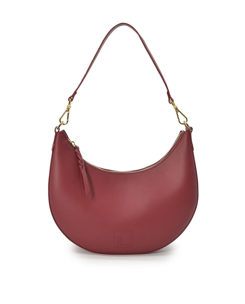Bolso imagen frontal asa corta de bolso de hombro multiposición con forma de media luna de piel color burdeos Leandra. 