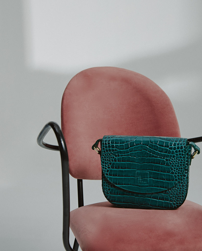 Imagen bodegón de bolso bandolera de piel grabada en coco verde con solapa fabricada en España Leandra