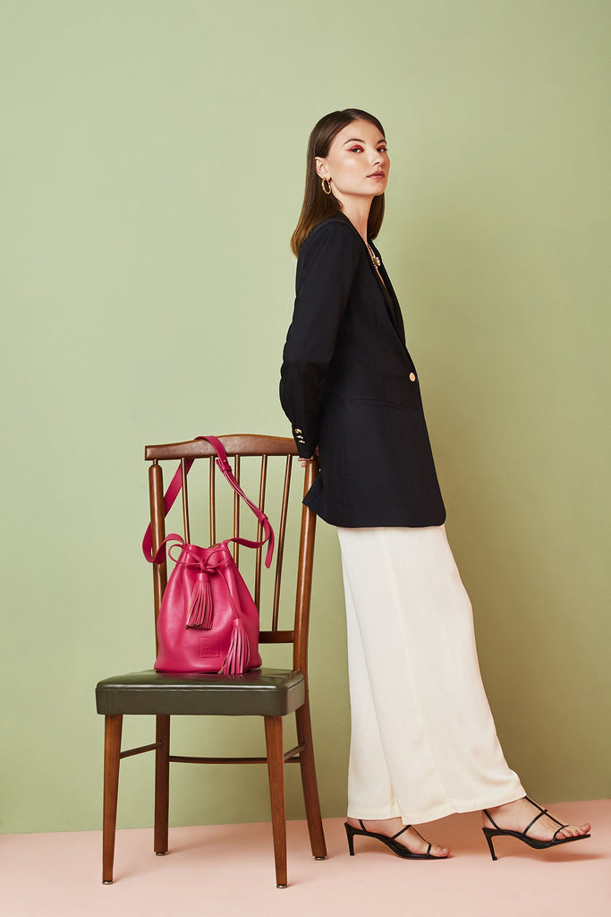 Imagen de modelo con silla y bolso saco piel suave fucsia Leandra. Bolso de piel  bucket bag Made in Spain Leandra