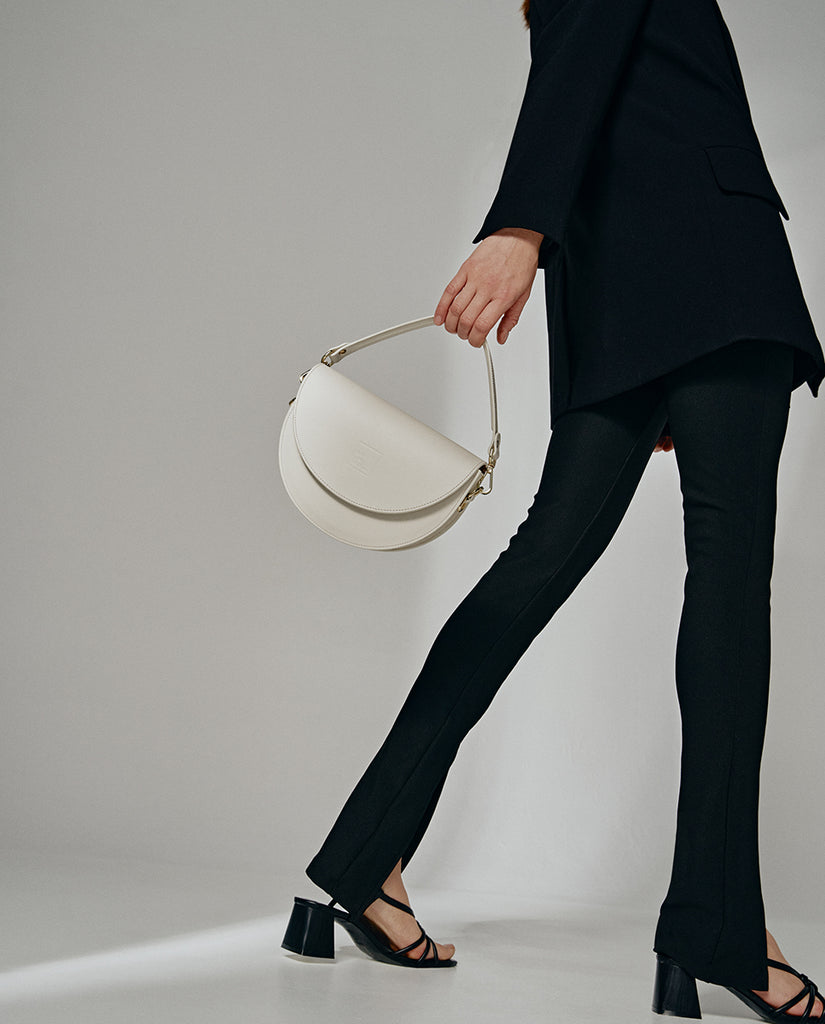 Imagen de modelo con B+bolso de piel tipo saddle bag color beige Leandra. Bolso bandolera de piel Leandra made in Spain