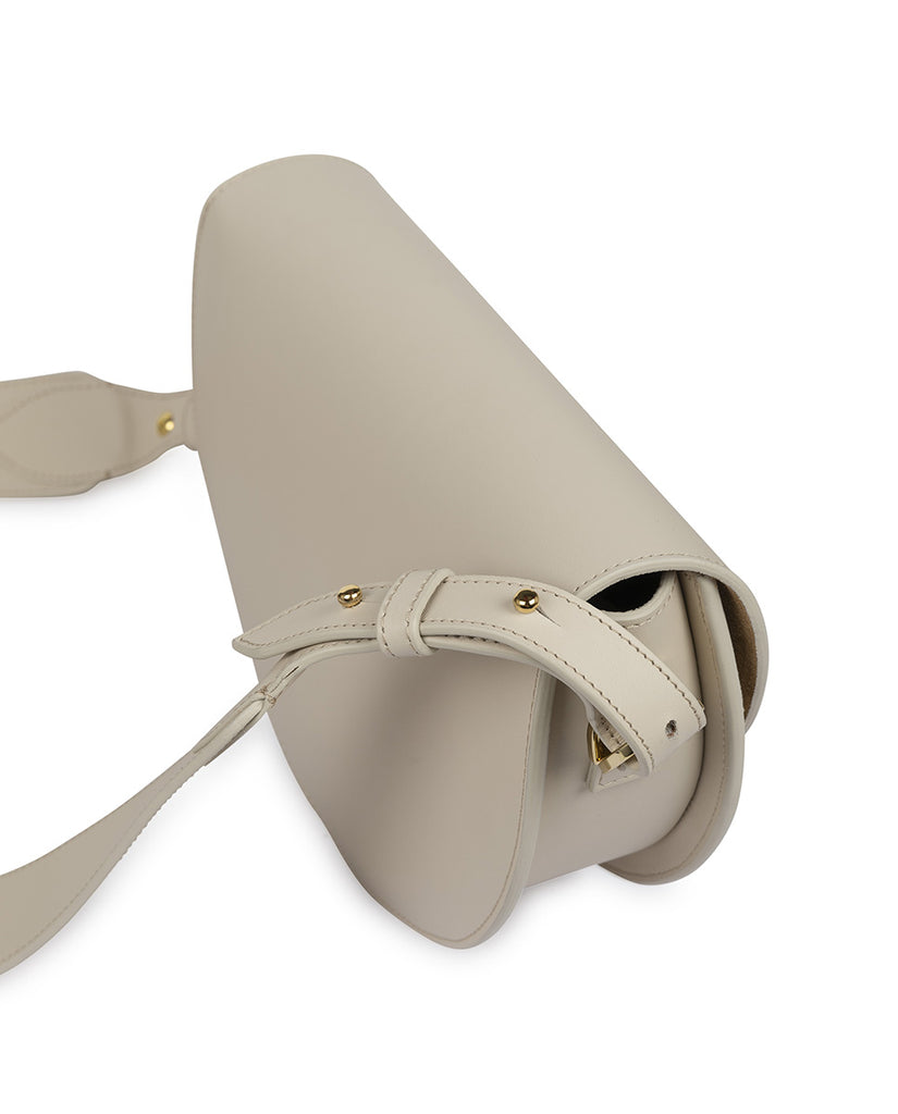 Imagen lateral de bolso tipo saddle bag color crema taupé Leandra. Bolso de piel Leandra