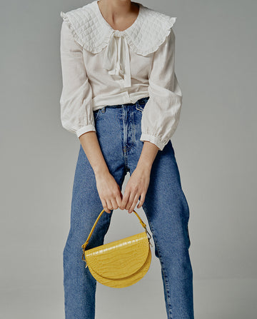 Imagen de modelo con bolso tipo Saddle bag de piel grabada en coco color amarillo Leandra. Bolsos de piel made in Spain Leandra