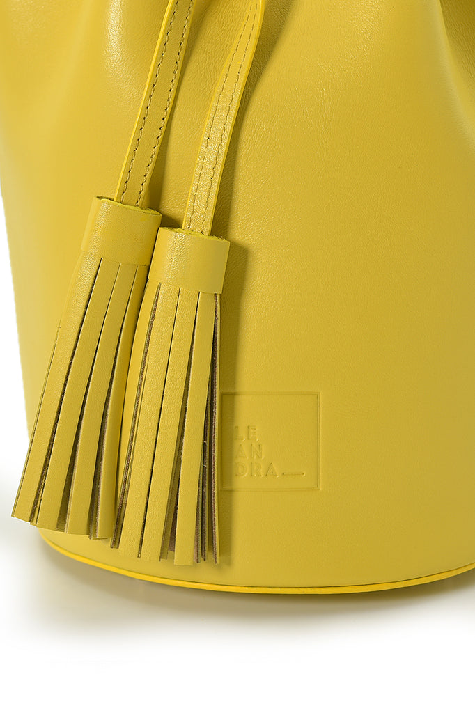 Borla Mini bolso de piel tipo saco o Mini bucket bag color amarillo con borlas bicolor en nude Leandra. Bolsos de piel Leandra. Imagen detalle borlas
