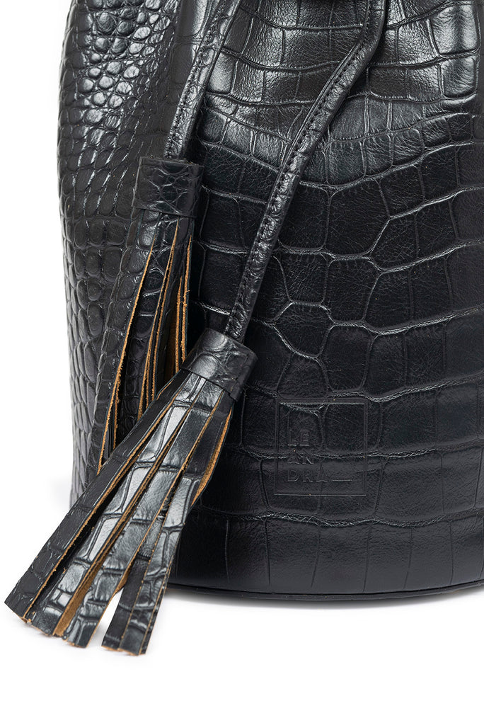 Bolso tipo bucket bag mini de piel vacuna grabada en coco negro Leandra. Bolso de piel fabricado en España Leandra. Imagen detalle borlas